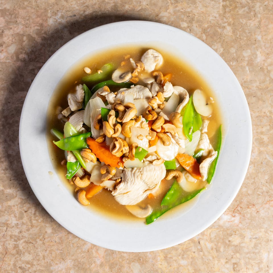 Chicken stir-fry with cashews, snow peas, carrots, mushrooms, and onions in a savory sauce.