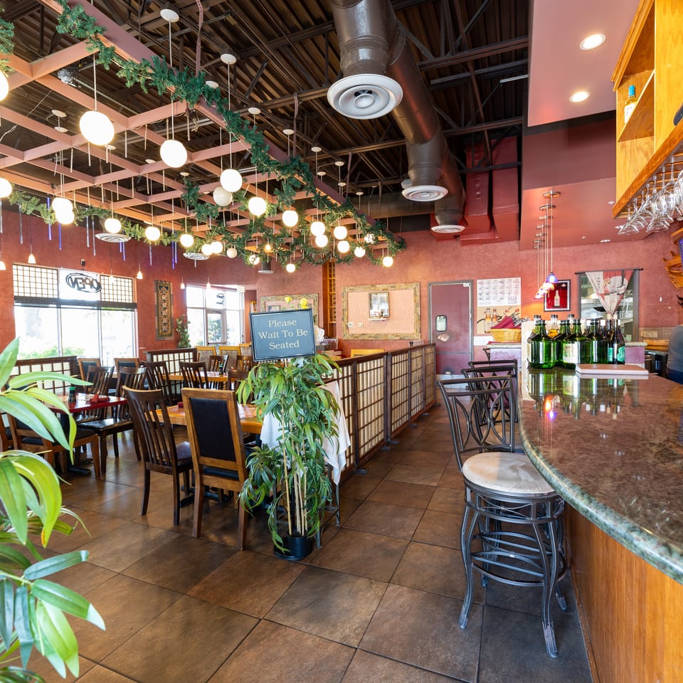 Spacious restaurant interior with dining tables, a bar, and festive ceiling decorations.
