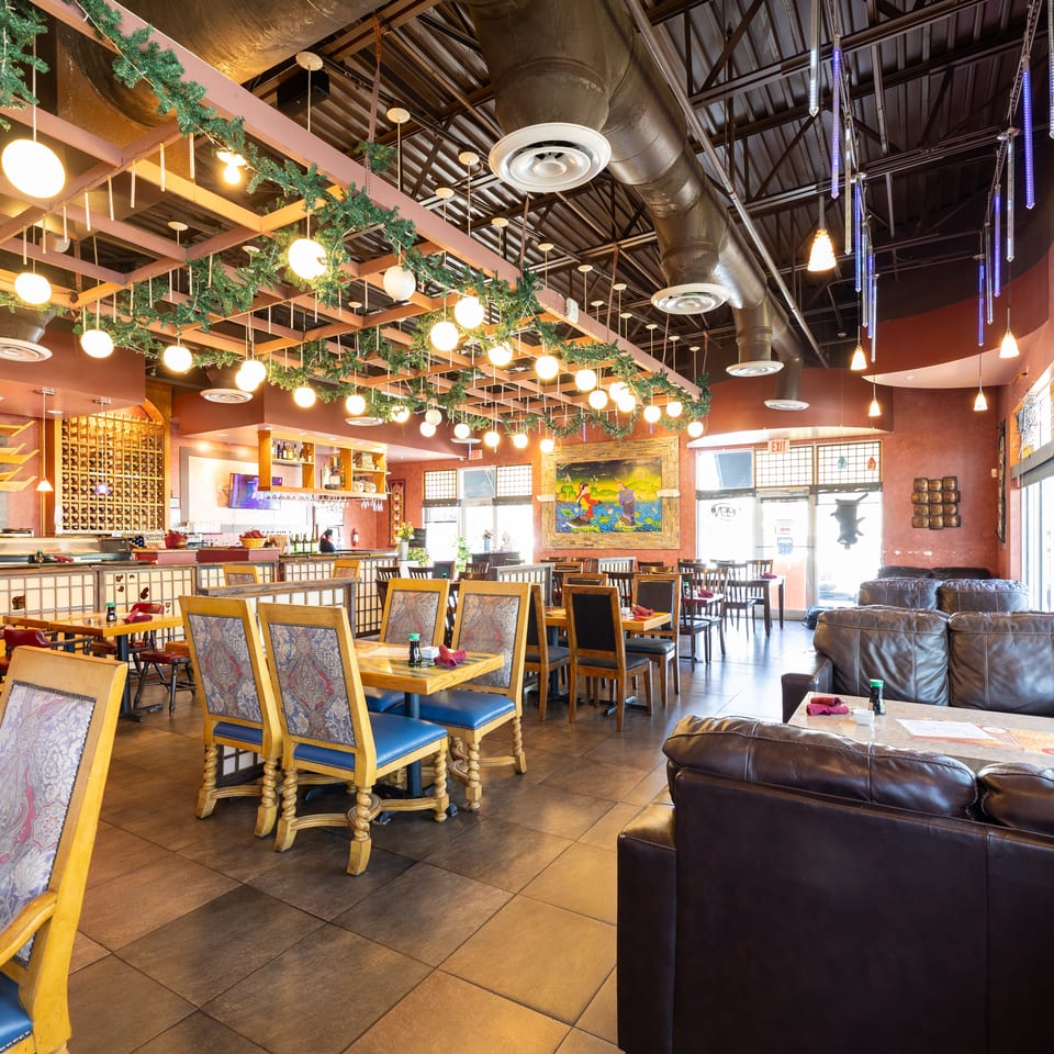 Spacious restaurant interior with diverse seating, including tables with patterned chairs and comfortable leather couches.